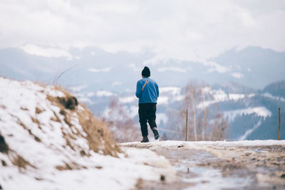 Rear view of man walking on mountain during winter