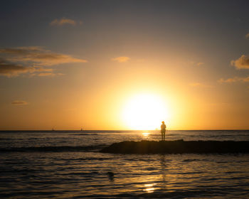 Woman watching sunset on the coast with calm ocean, shot at waikiki beach, honolulu, hawaii, usa