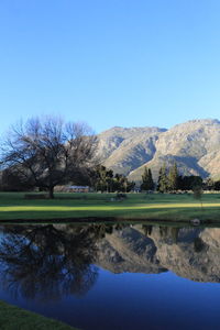 Scenic view of lake and mountains against clear blue sky