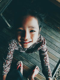 Directly above portrait of cute girl standing on wooden floor