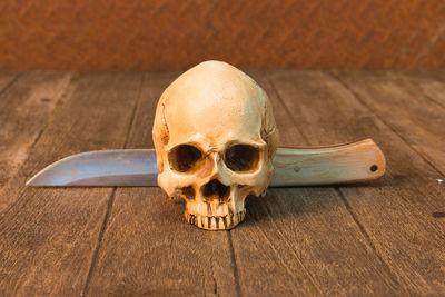 Close-up of human skull and knife on table