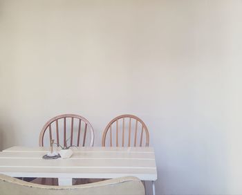 Empty chairs and table against wall