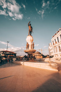 Statue in city against sky