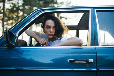 Portrait of woman sitting on car window