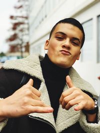 Portrait of young man gesturing while standing outdoors