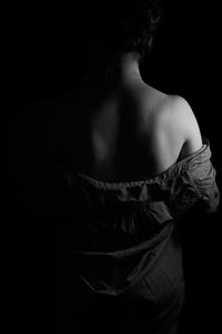 Rear view of woman standing against black background