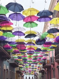 Low angle view of multi colored umbrellas hanging in city