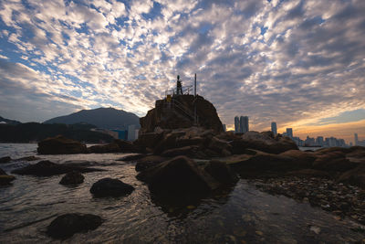 Rock formations by sea against sky during sunset