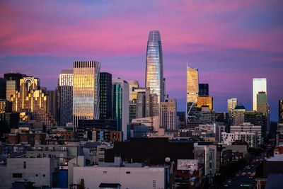 Modern buildings in city against sky during sunset