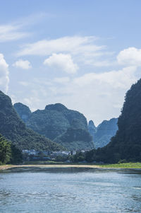 Scenic view of river by mountains against sky