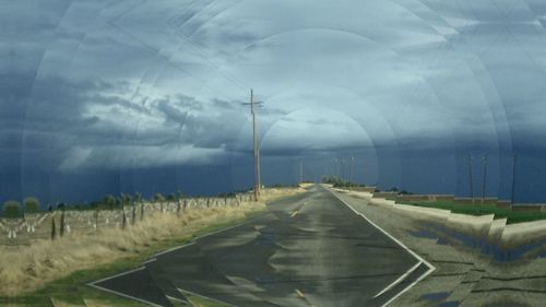 Road in field against storm clouds