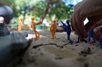 Cropped hand playing with figurines at beach