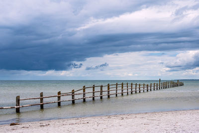 Wooden posts on beach against sky