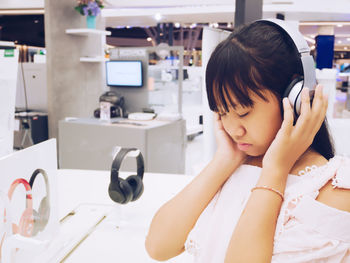 Teenage girl wearing headphones while standing at store