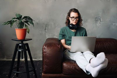 Young man using laptop while sitting on sofa at home