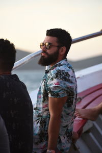 Young man looking away while standing in boat