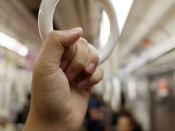 Cropped hand holding handle in illuminated train