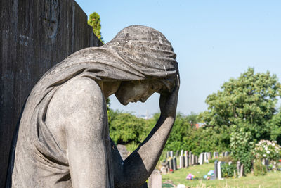 Close-up of angel statue in cemetery against sky