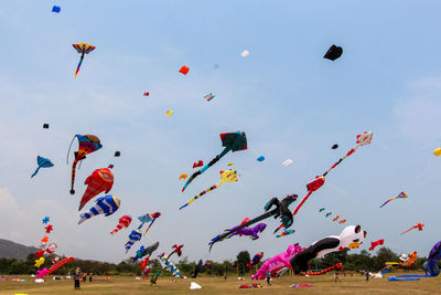 Colorful kites flying over landscape against sky