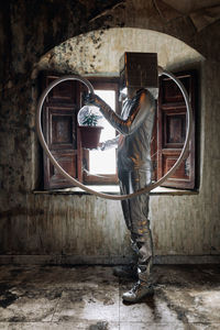 Man holding umbrella standing against wall