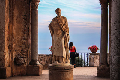 Rear view of woman standing by statue 