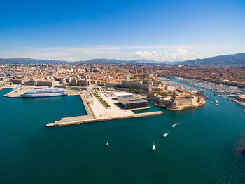 High angle view of sea and buildings against blue sky