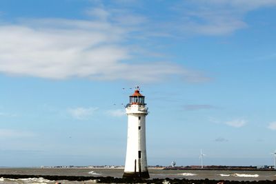 Lighthouse by sea against sky