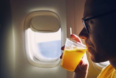Close-up of man drinking juice while sitting in airplane
