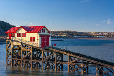 Stilt houses by sea against sky