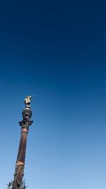 Low angle view of statue against clear blue sky during sunny day