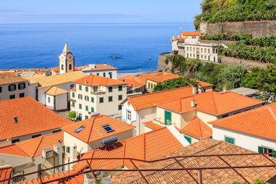 High angle view of townscape by sea against sky