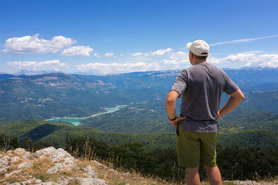 Rear view of man standing on mountain against sky