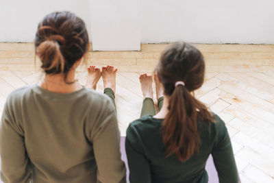 Attractive mother middle age woman and daughter teenager ptactice yoga together in the bright studio