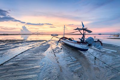 Boats moored on sea against sky during sunset