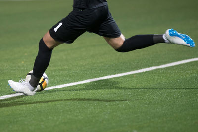 Low section of man playing soccer on field