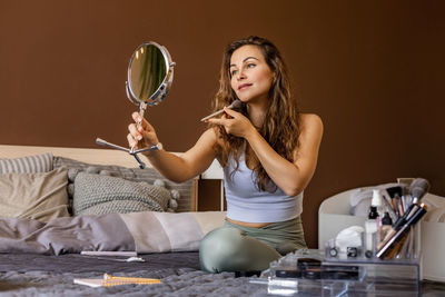 Portrait of smiling young woman sitting on bed at home