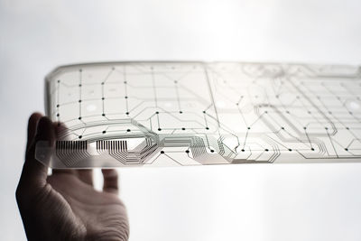 Close-up of hand holding transparent material against white background