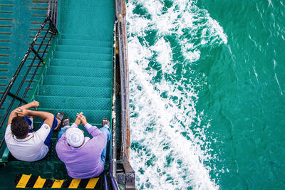 High angle view of men sitting in ferry sailing on sea