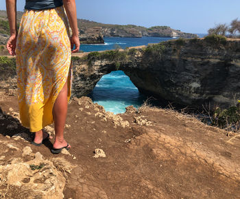 Low section of woman standing on land over sea