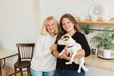 Portrait of young woman with dog sitting on hardwood floor at home