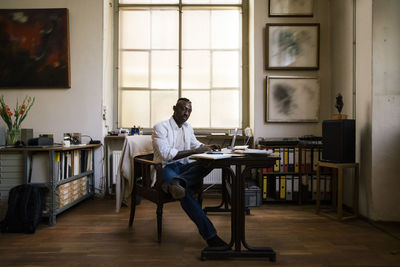 Male entrepreneur sitting on chair by table in workshop