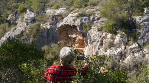 Rear view of woman photographing on mobile phone against mountain