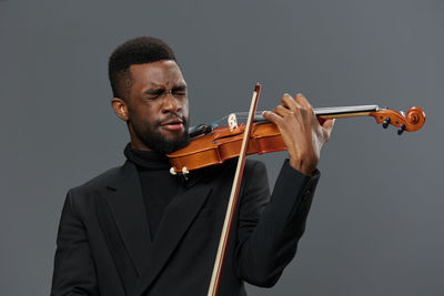 Midsection of man playing violin against white background