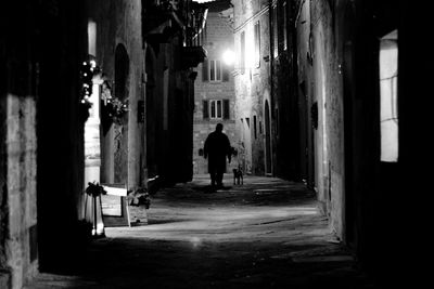 Rear view of man walking in illuminated corridor of building