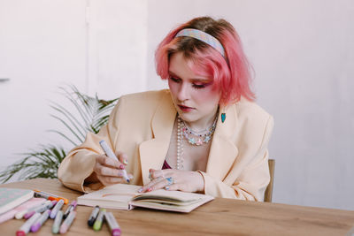 Portrait of young woman using mobile phone while sitting on table