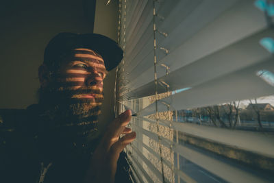 Low angle view of young man looking through window