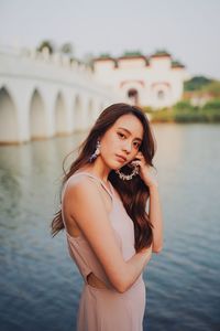 Young woman standing against bridge over water