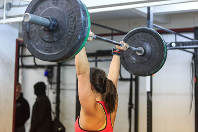 Rear view of a woman exercising with barbell