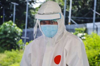 Portrait of man wearing mask standing against plants