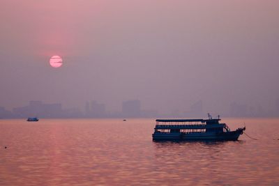 Boat sailing in sea against sky during sunset